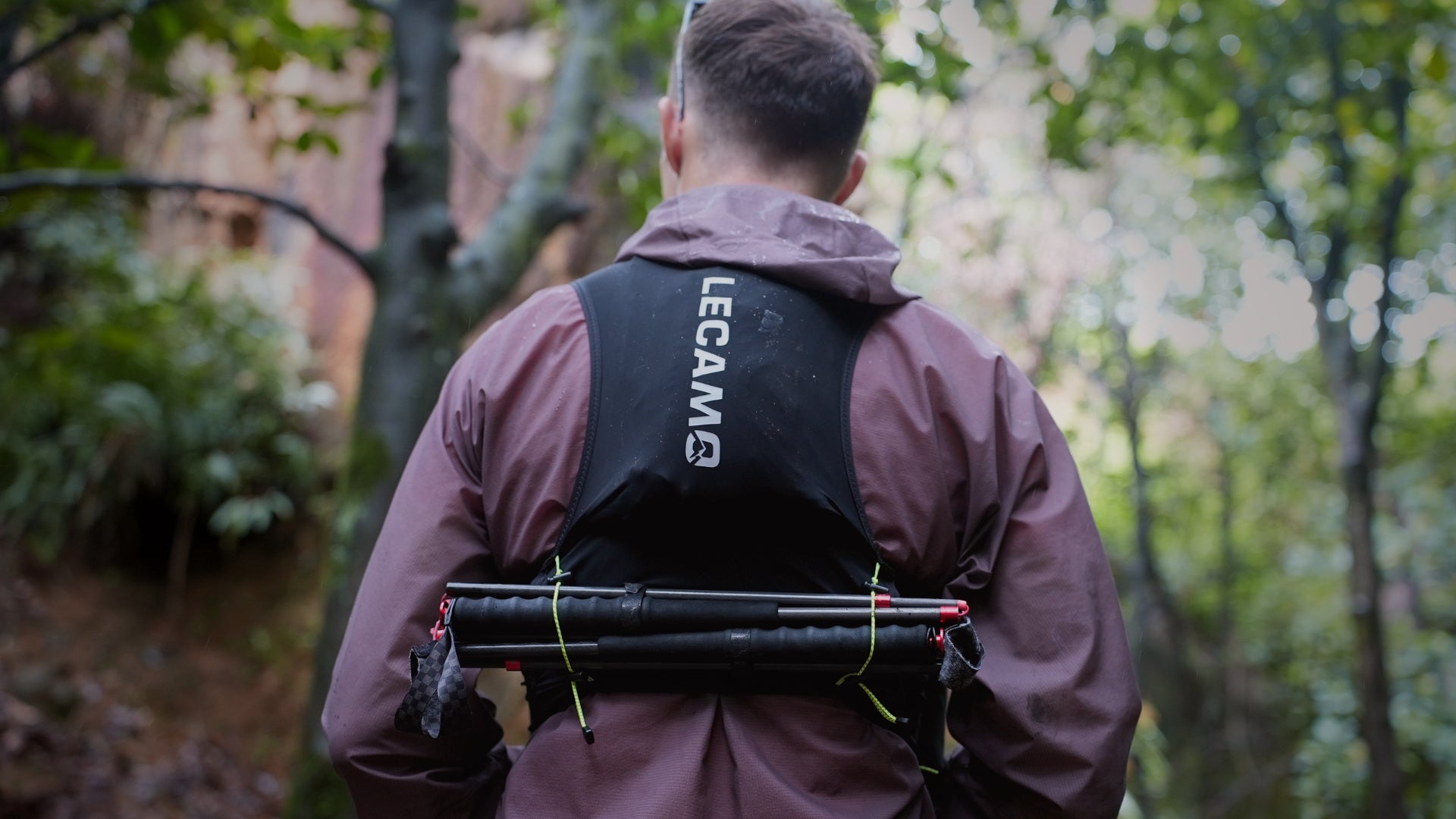 LECAMO runner carrying poles through a forest