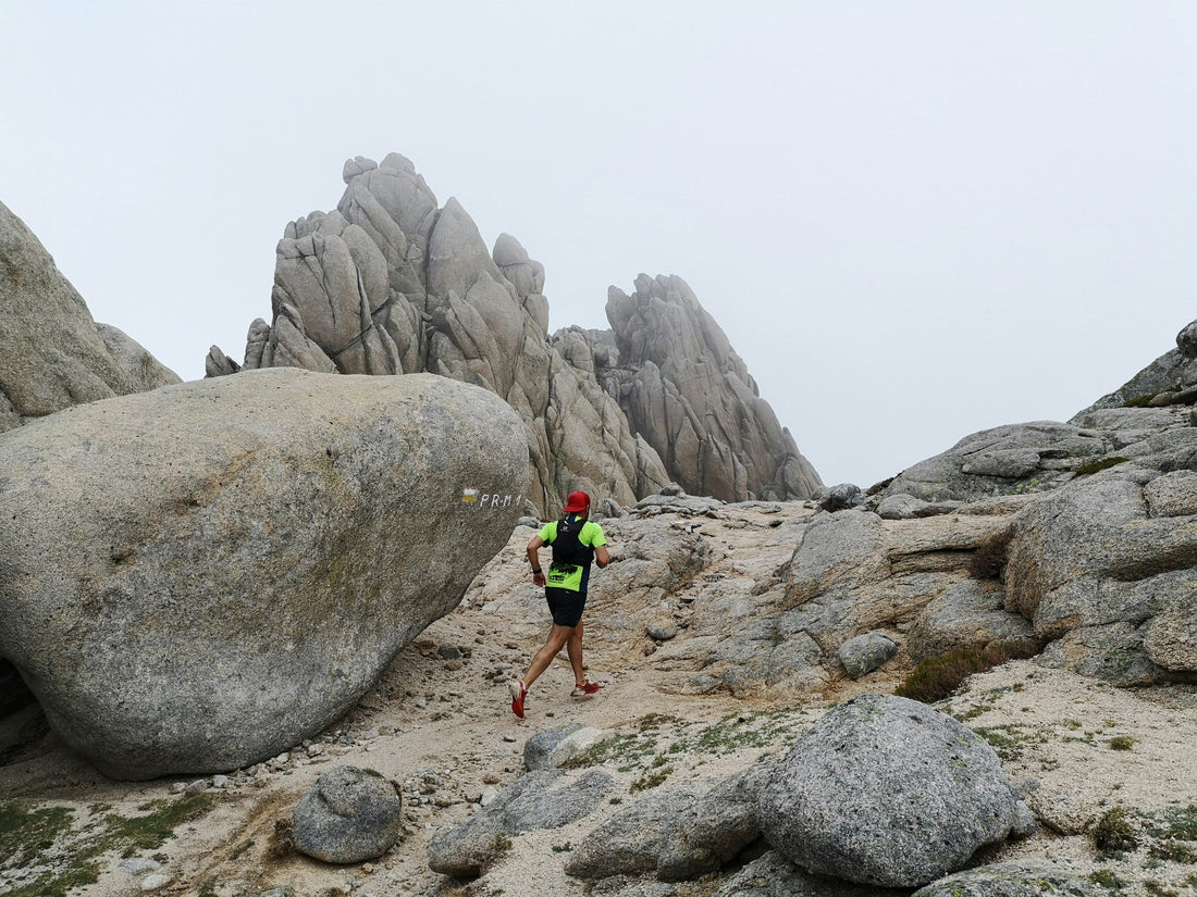 Trail runner crossing rocky terrain in Spain beneath a pale sky