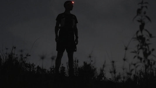 Trail runner wearing a headlamp in low light on a hillside