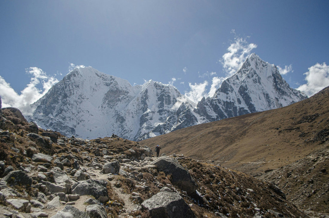 Hiker on a rocky trail below snowy Himalayan peaks in Nepal