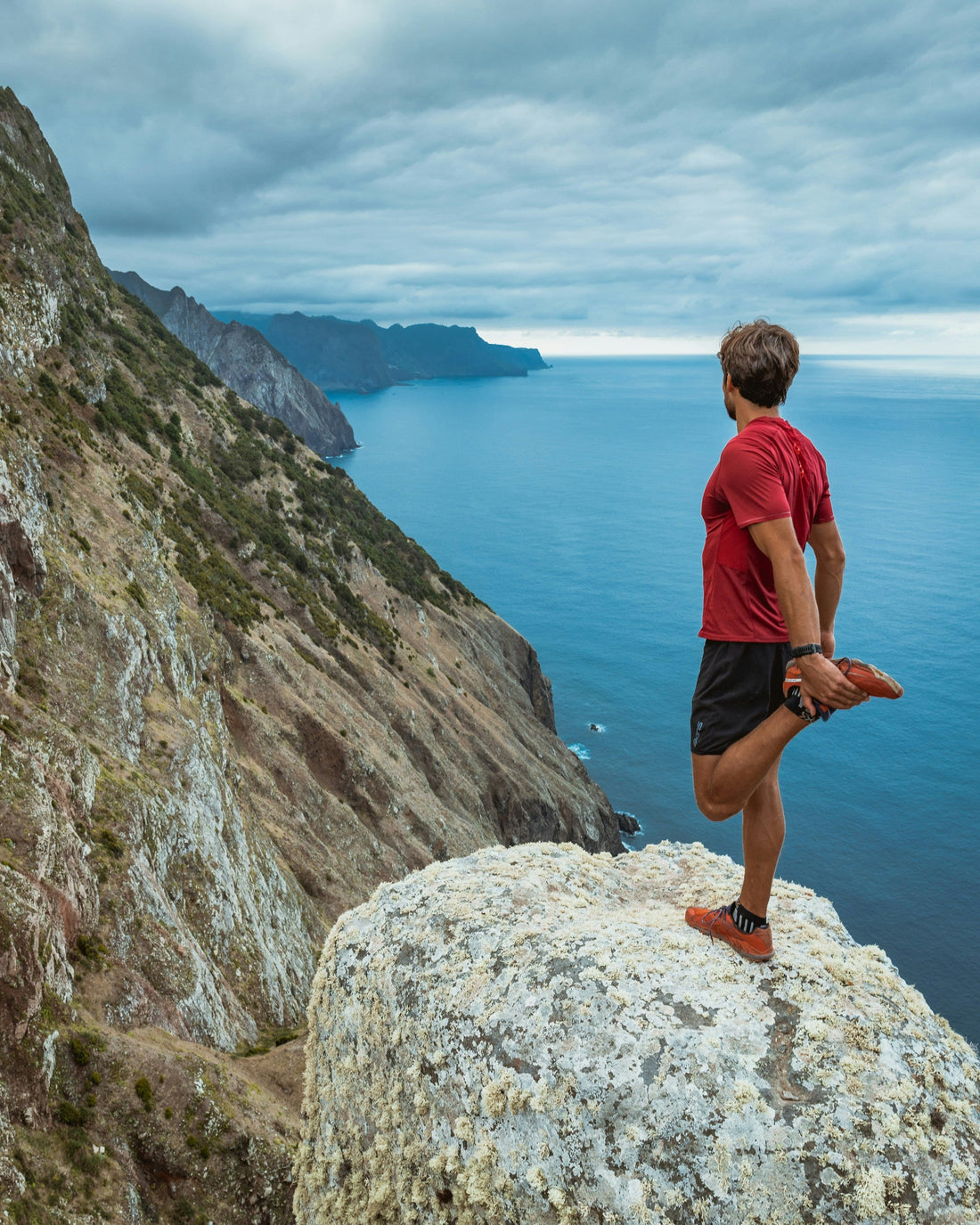 Runner stretching on a rocky coast in Madeira, Portugal