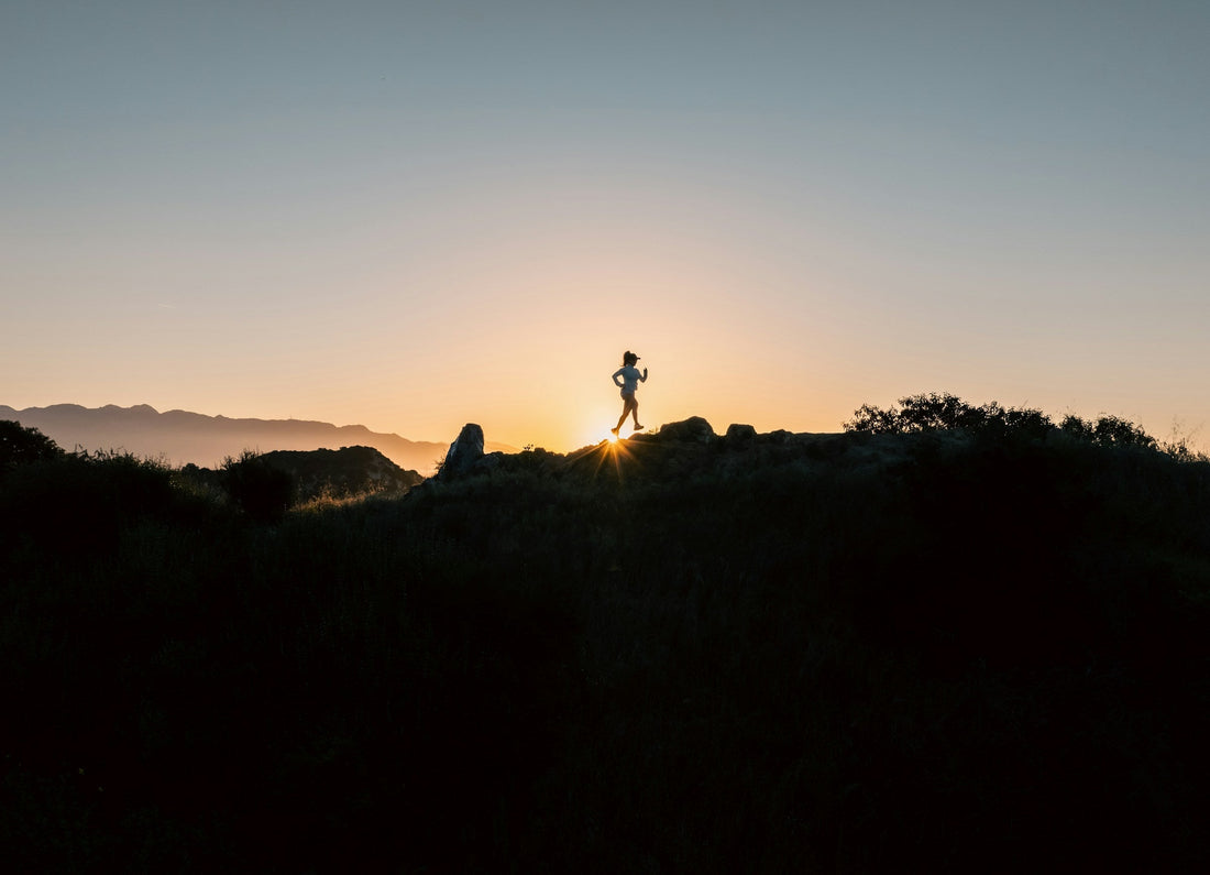 Silhouette of a trail runner on a rocky ridge at sunset in Los Angeles
