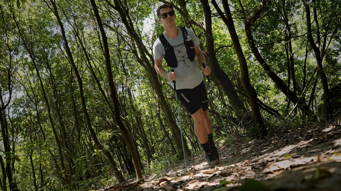 LECAMO trail runner climbing through forest with hydration vest and trekking poles