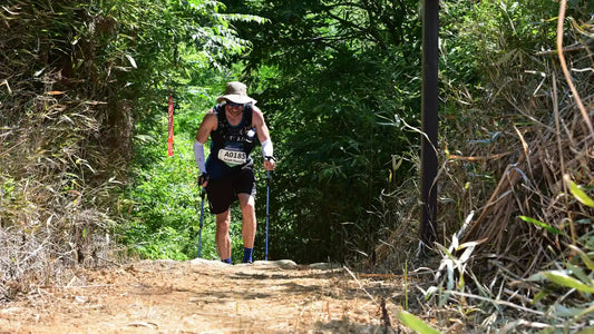 Trail runner climbing a forest trail with trekking poles