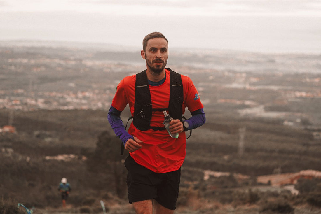 Runner in a red shirt carrying a flask on a rocky trail