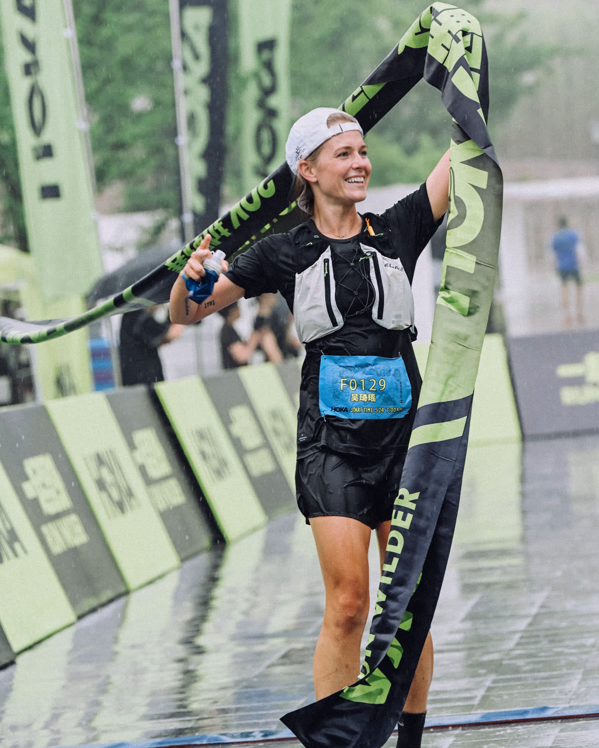 Trail runner celebrating at a rainy race finish