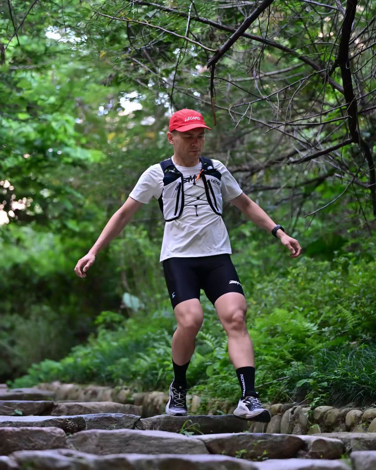 Trail runner descending stone steps in a LECAMO vest