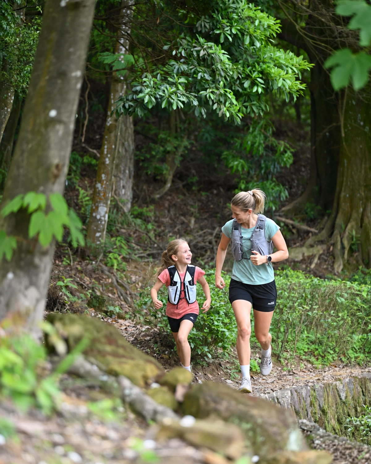 Mother and daughter trail running together through a forest